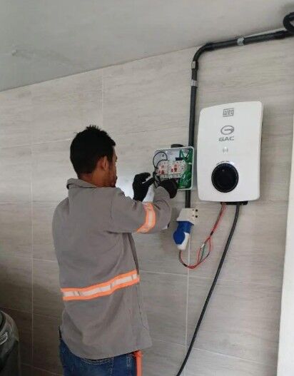 Técnico instalando carregador veicular Weg GAC em parede residencial