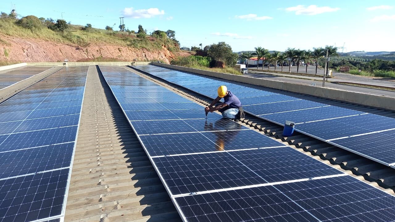 Técnico instalando painel solar fotovoltaico em telhado comercial